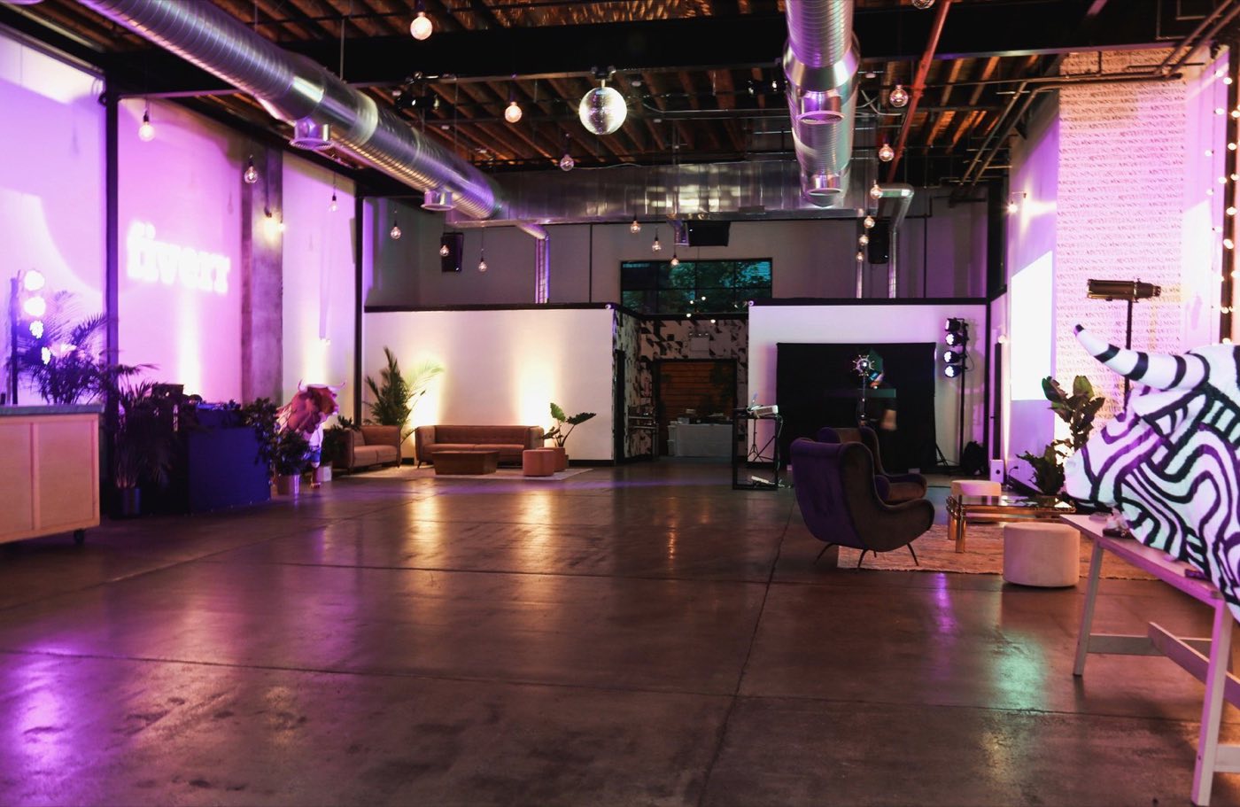 Main space lit in purple with a disco ball and lounge seating
