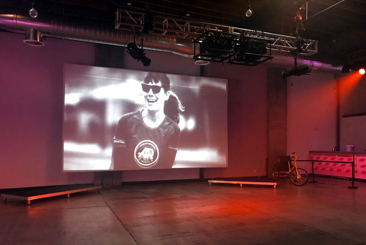 Screening in the main space with a projector screen and red stage lighting