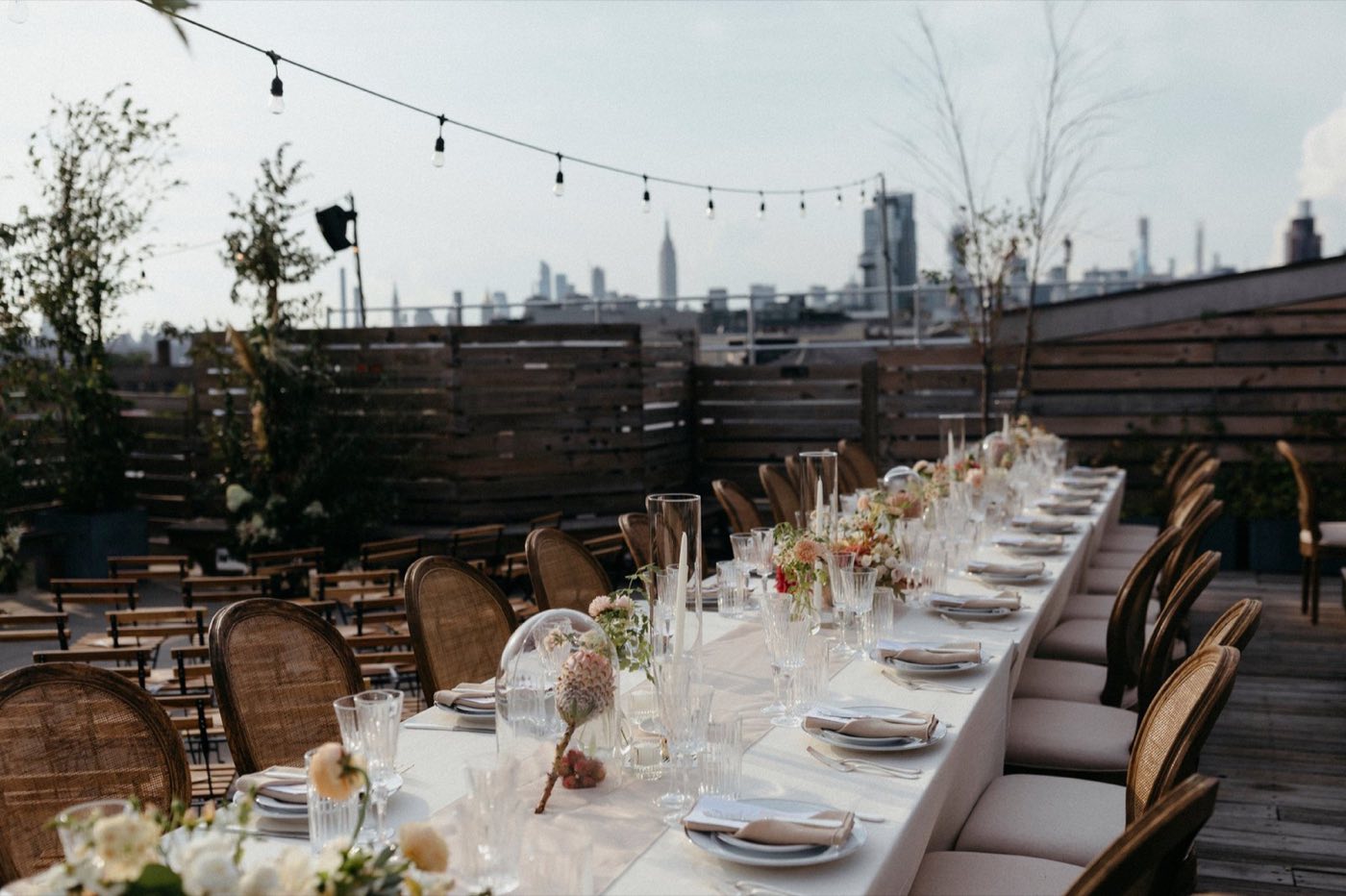 Rooftop terrace set with a long dinner table and a Manhattan skyline view