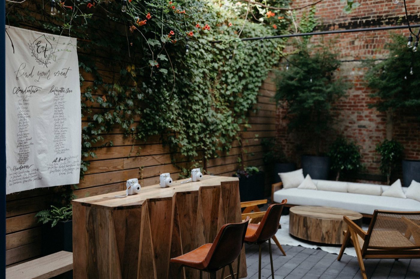 Courtyard with ivy-covered walls, wood tables and lounge seating