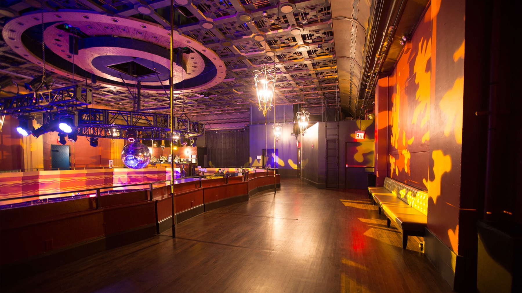 Empty balcony level dance floor with ornate coffered ceiling, chandeliers and mirror ball