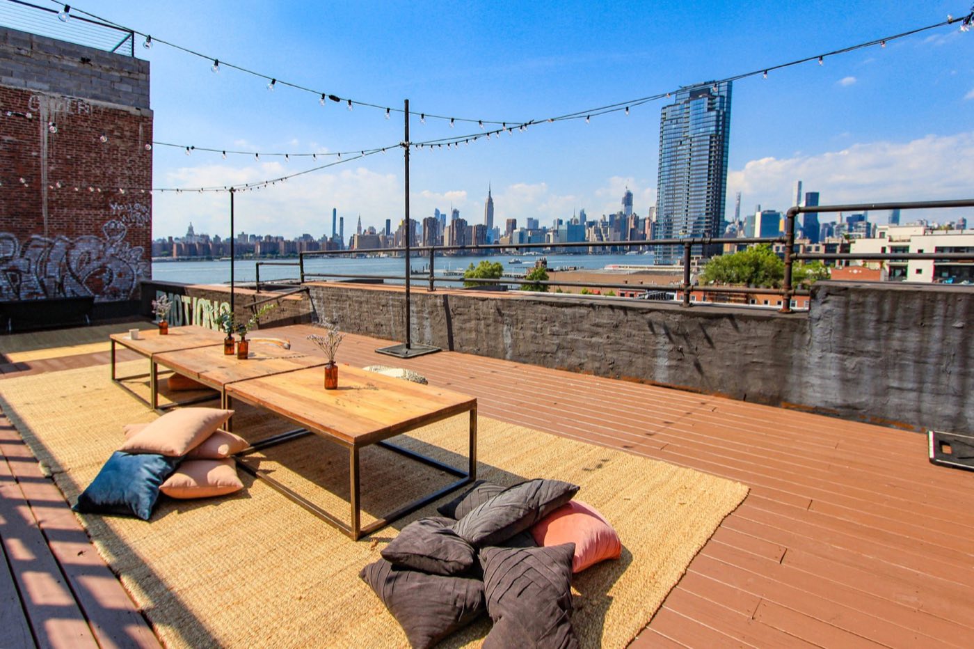 Rooftop deck with low tables and floor cushions facing the Manhattan skyline