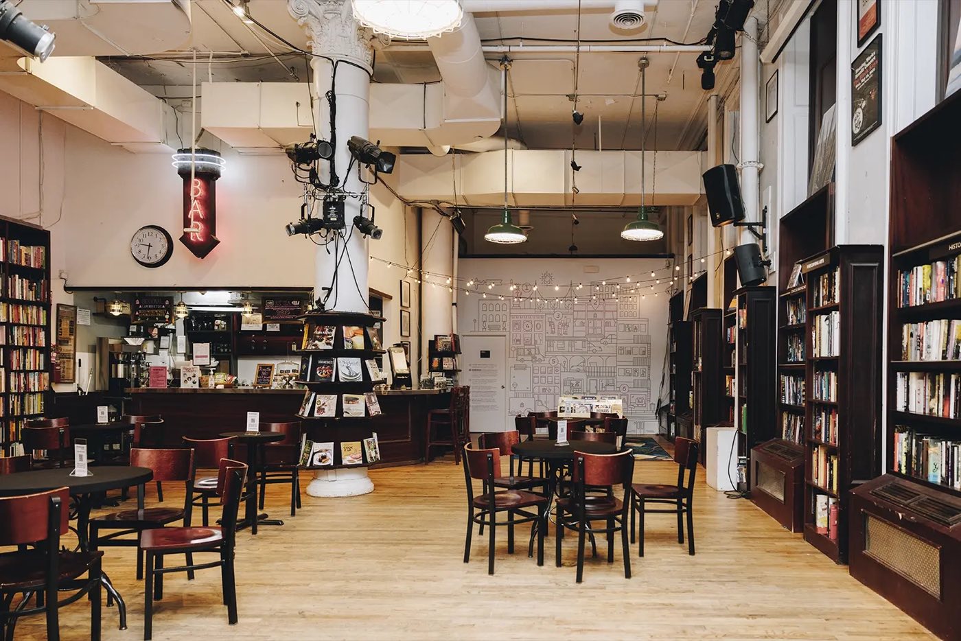 Empty cafe floor with bistro tables, tall bookshelves and white columns