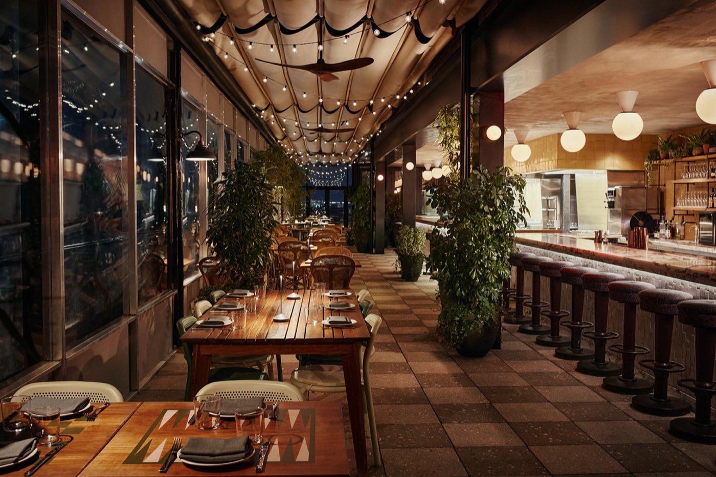 Laser Wolf rooftop dining room with long bar, plants and wall of windows