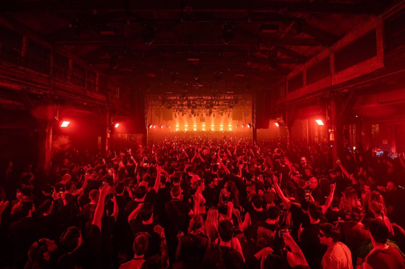 Main hall during a concert, lit red, showing the long industrial room and roof trusses