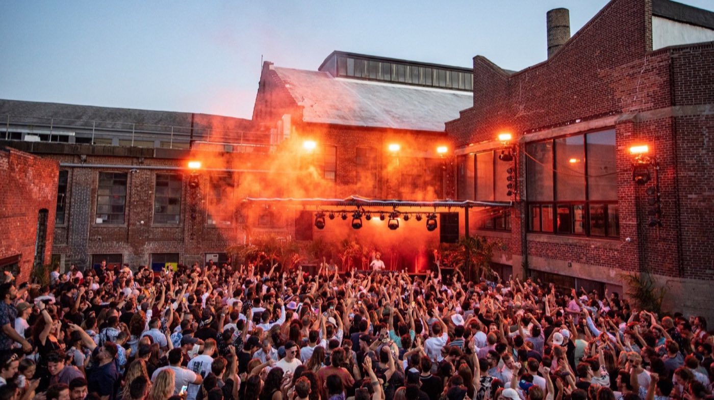 Outdoor Ruins courtyard stage framed by brick factory walls at dusk