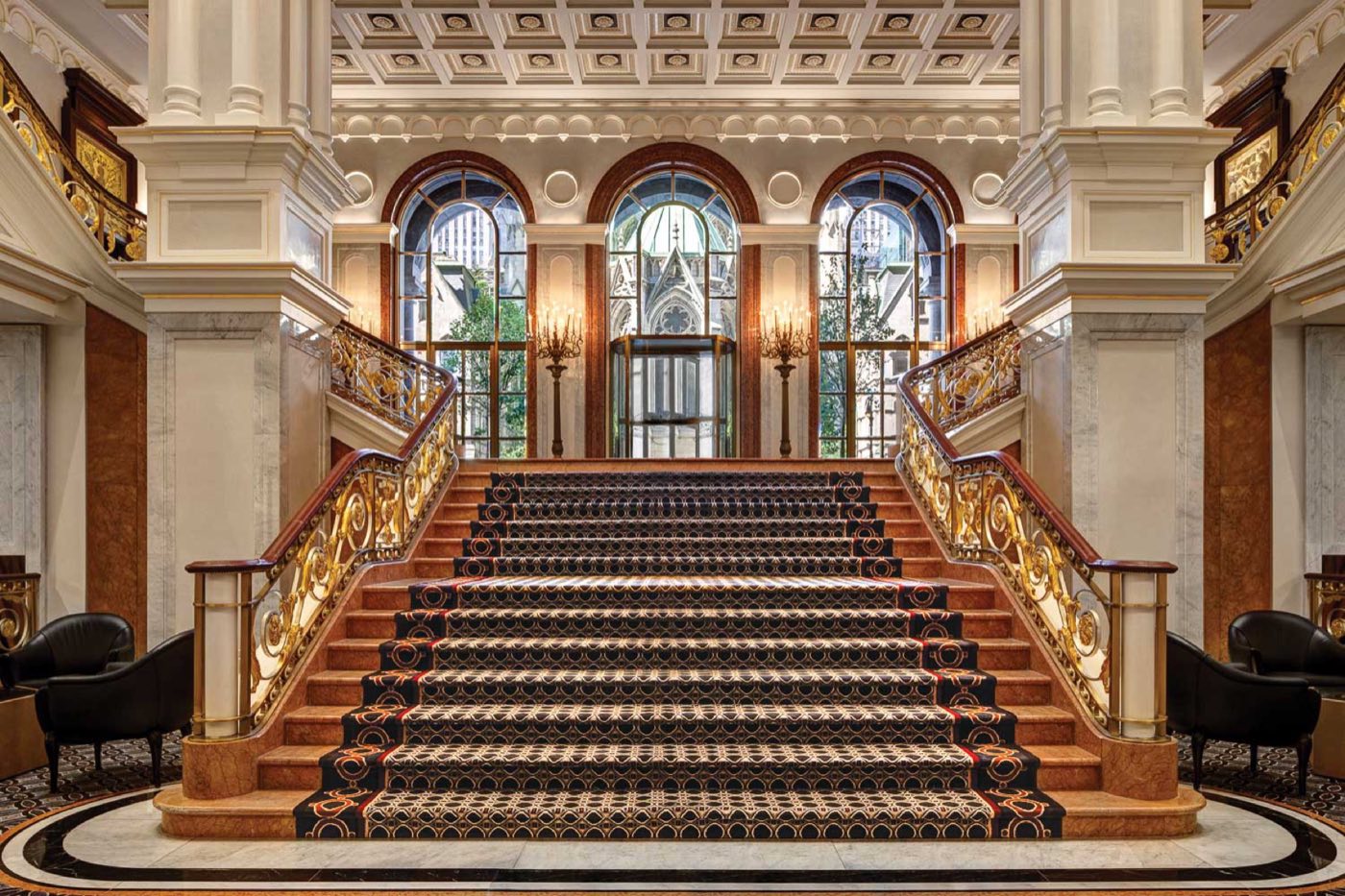 Grand marble staircase with gilded railings and arched windows in the mansion