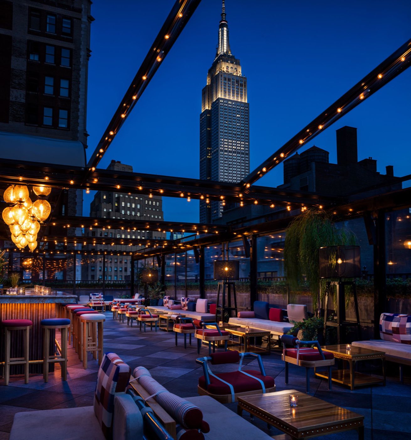 East Terrace at dusk under a steel roof frame facing the Empire State Building
