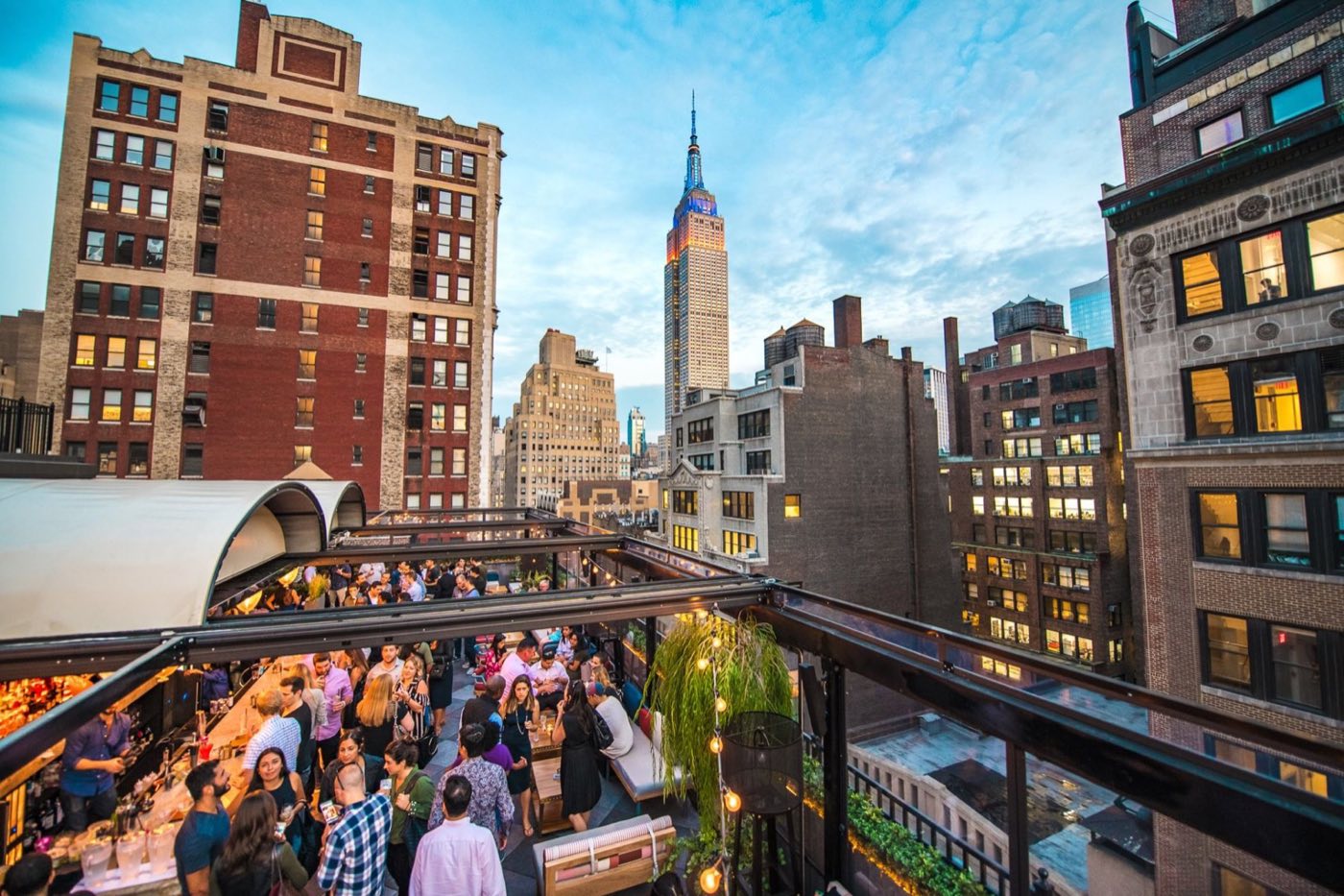 Crowded rooftop party on the terrace with Midtown towers and the Empire State Building