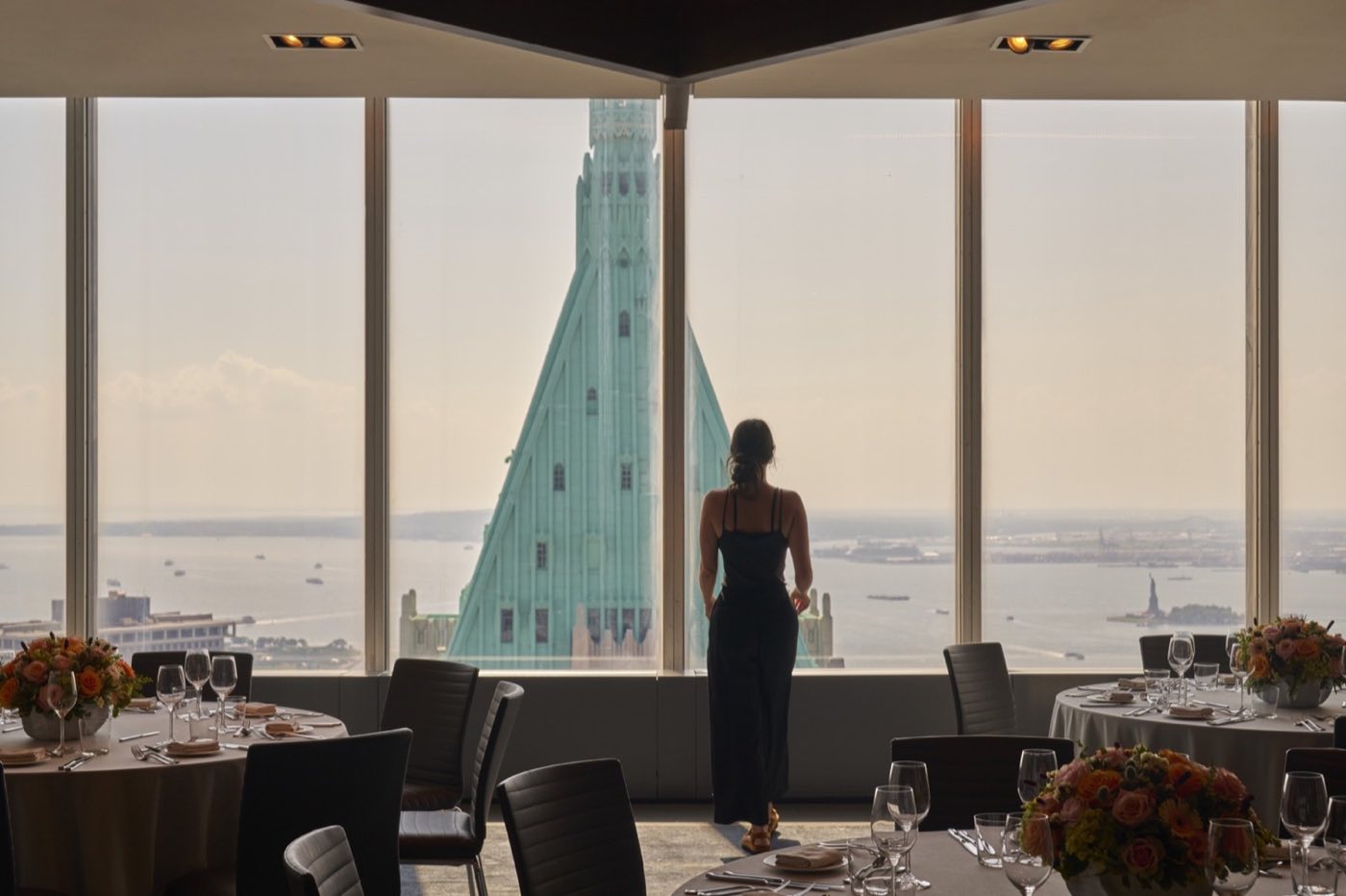 Sixtieth floor dining room with round tables and a view of the harbor