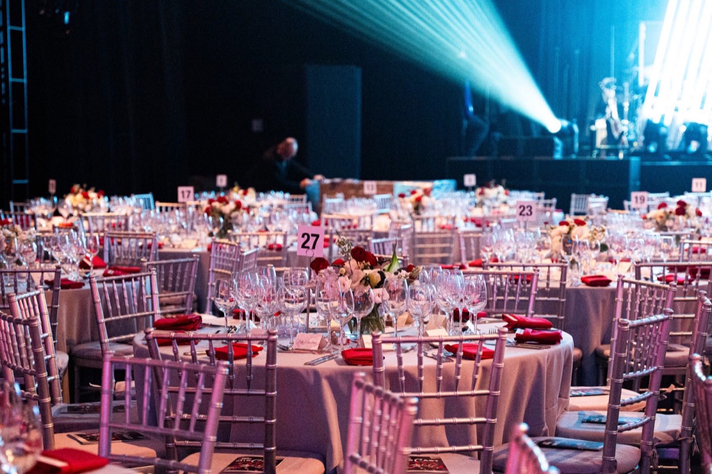 Ballroom set with round banquet tables in front of a lit stage