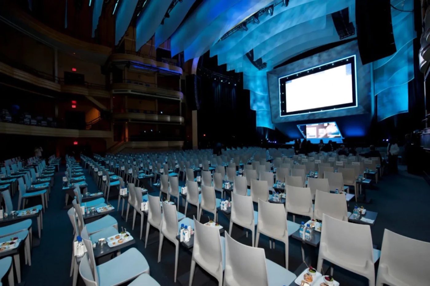 Ballroom set conference style with rows of chairs and a stage screen