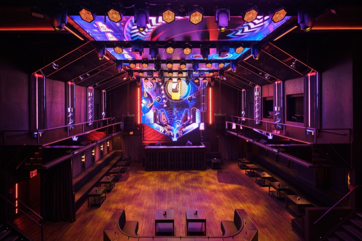 Empty main room with LED stage wall, booths along the sides and a mezzanine rail