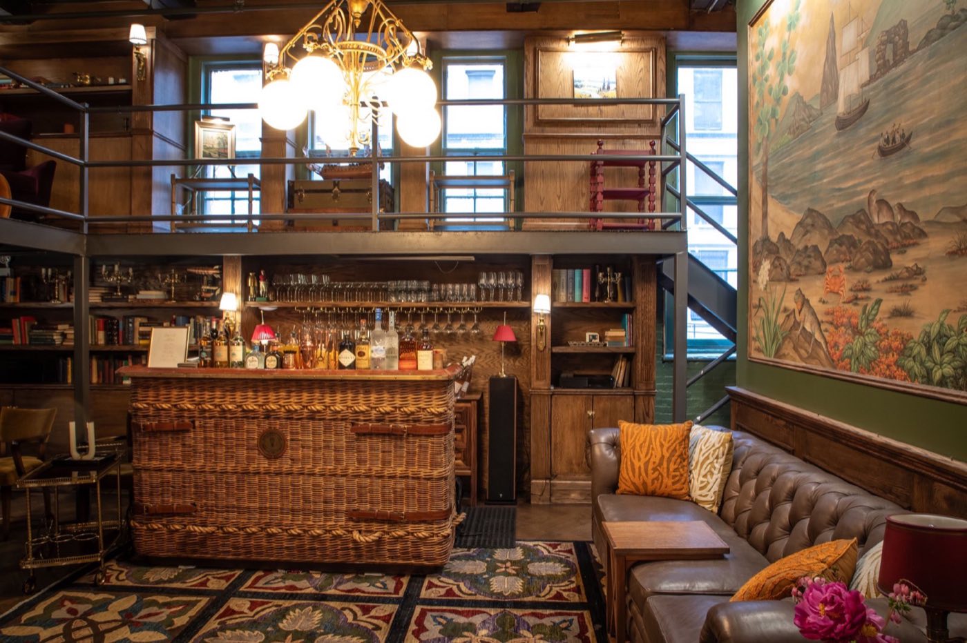 Bar room with wicker bar front, mezzanine bookshelves and painted mural
