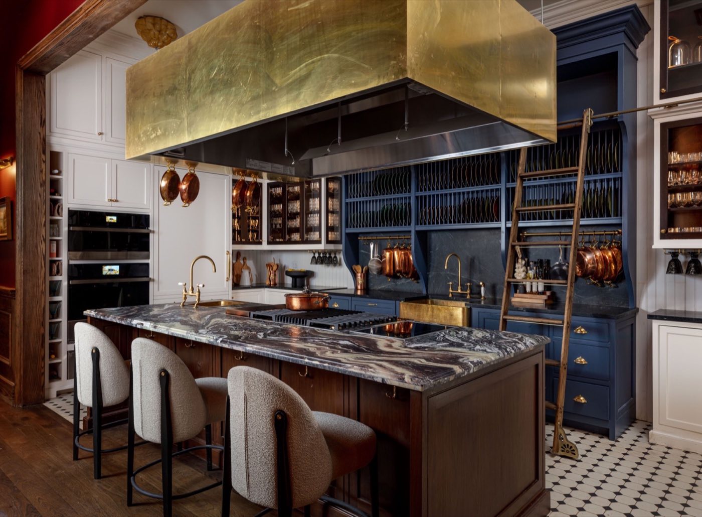 Demonstration kitchen with marble island, brass hood and bar stools