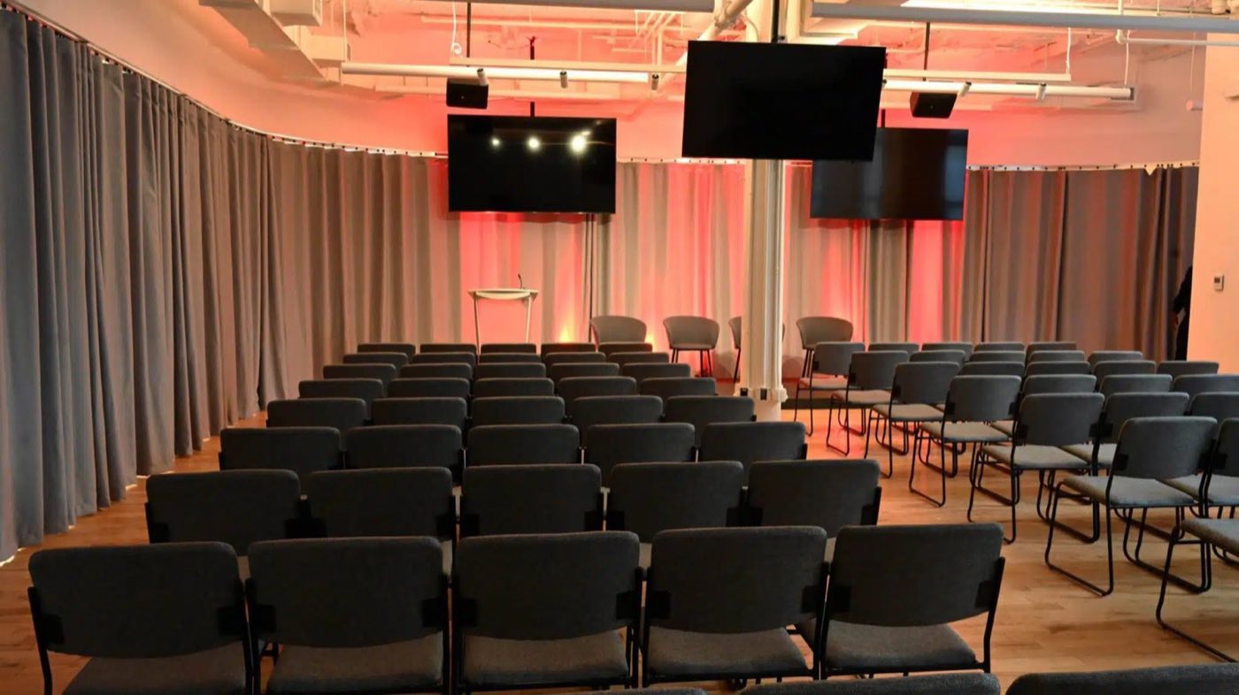 Event room set theater style with drapes and wall-mounted screens