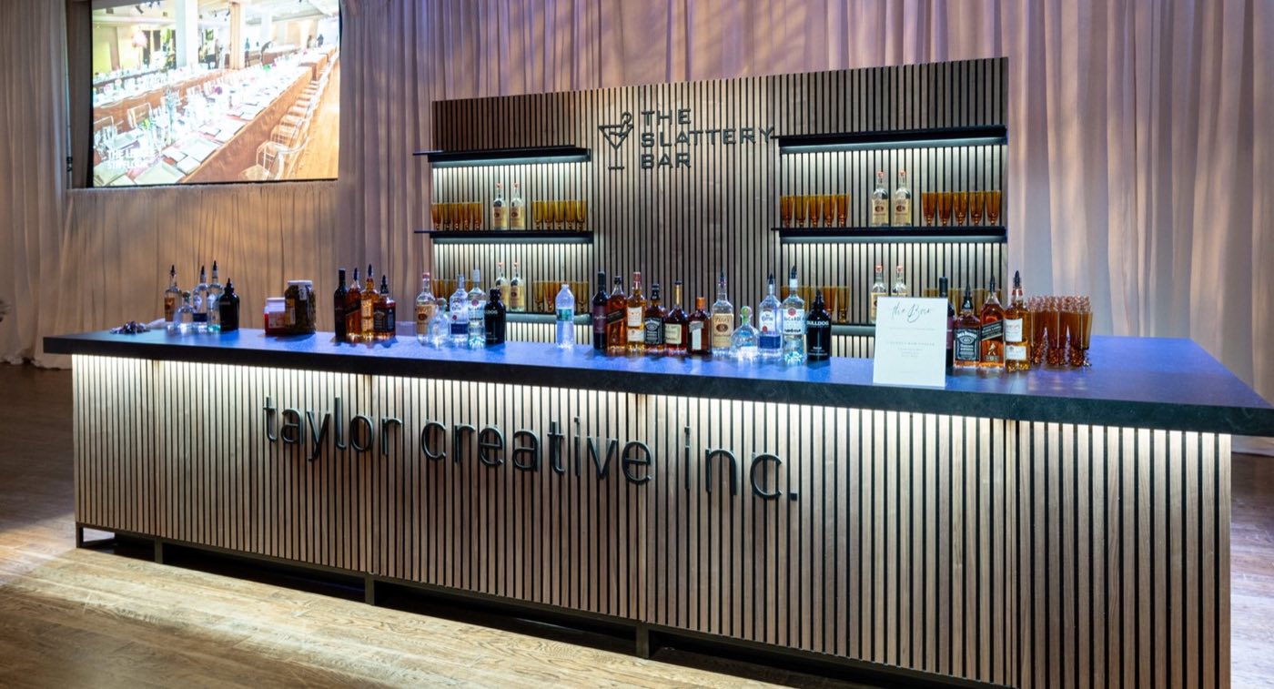 Branded bar counter with backlit shelving and a screen above