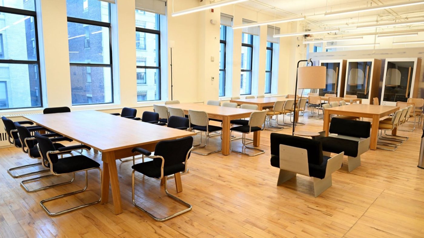 Meeting room with wood tables, office chairs and tall windows