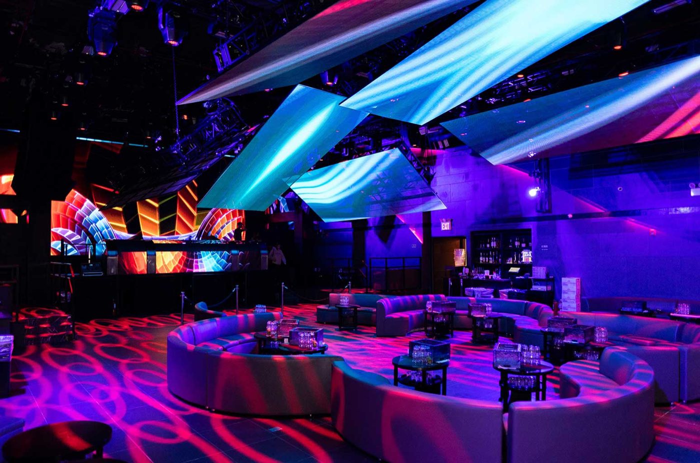 Main room with booth seating, gobo lighting on the floor and hanging LED screens