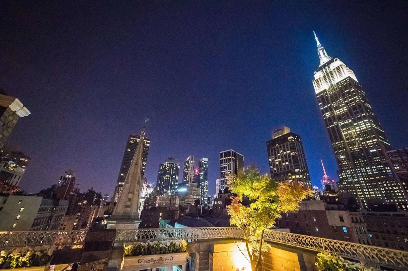 Rooftop terrace at night with the Empire State Building lit behind