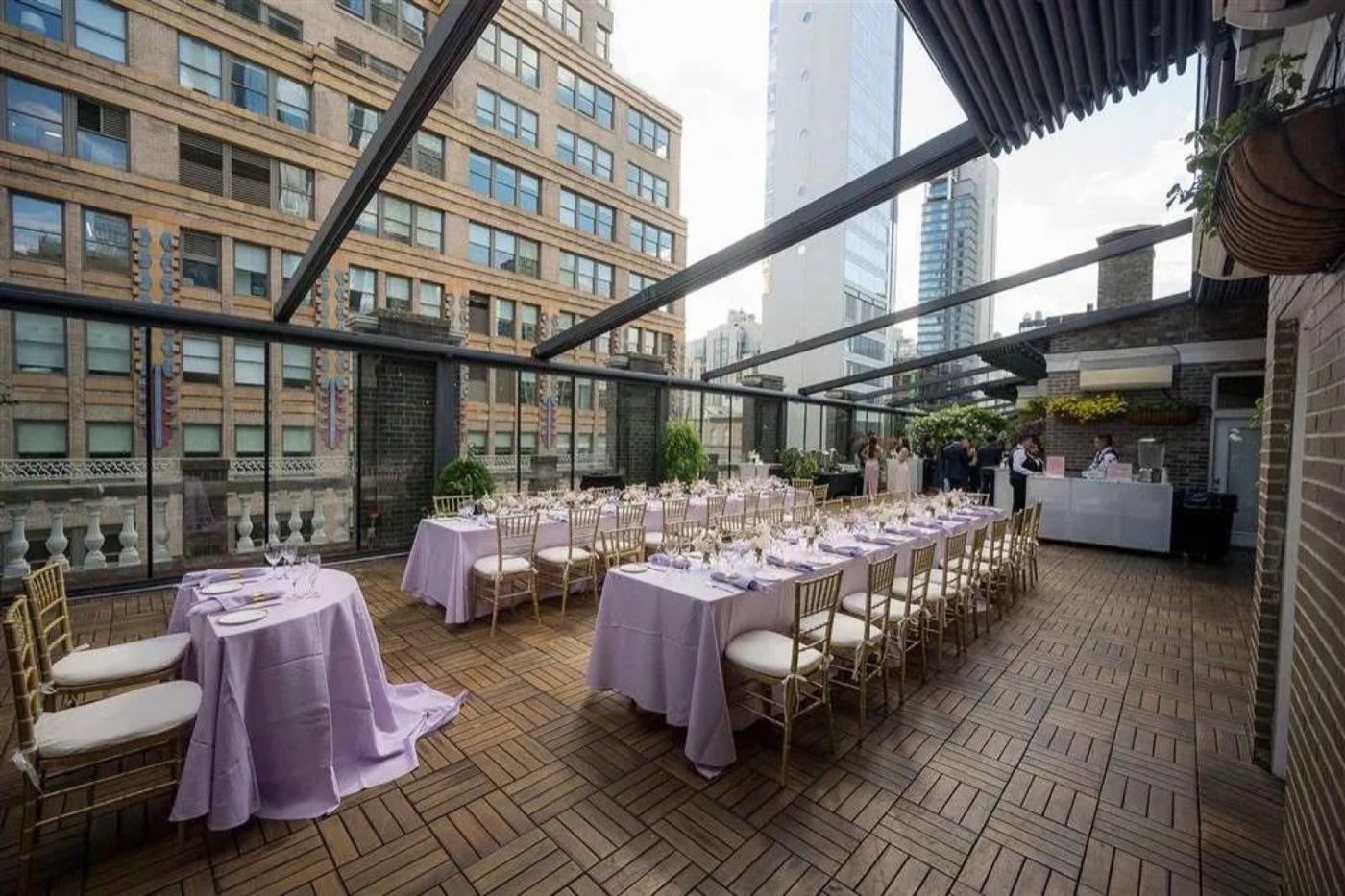 Covered terrace set with long dinner tables and city views