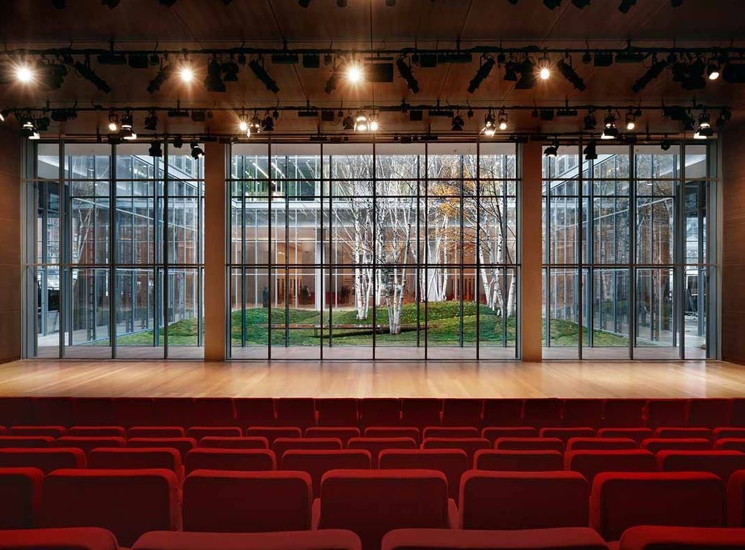 Wood stage framed by floor to ceiling glass looking onto a birch tree garden