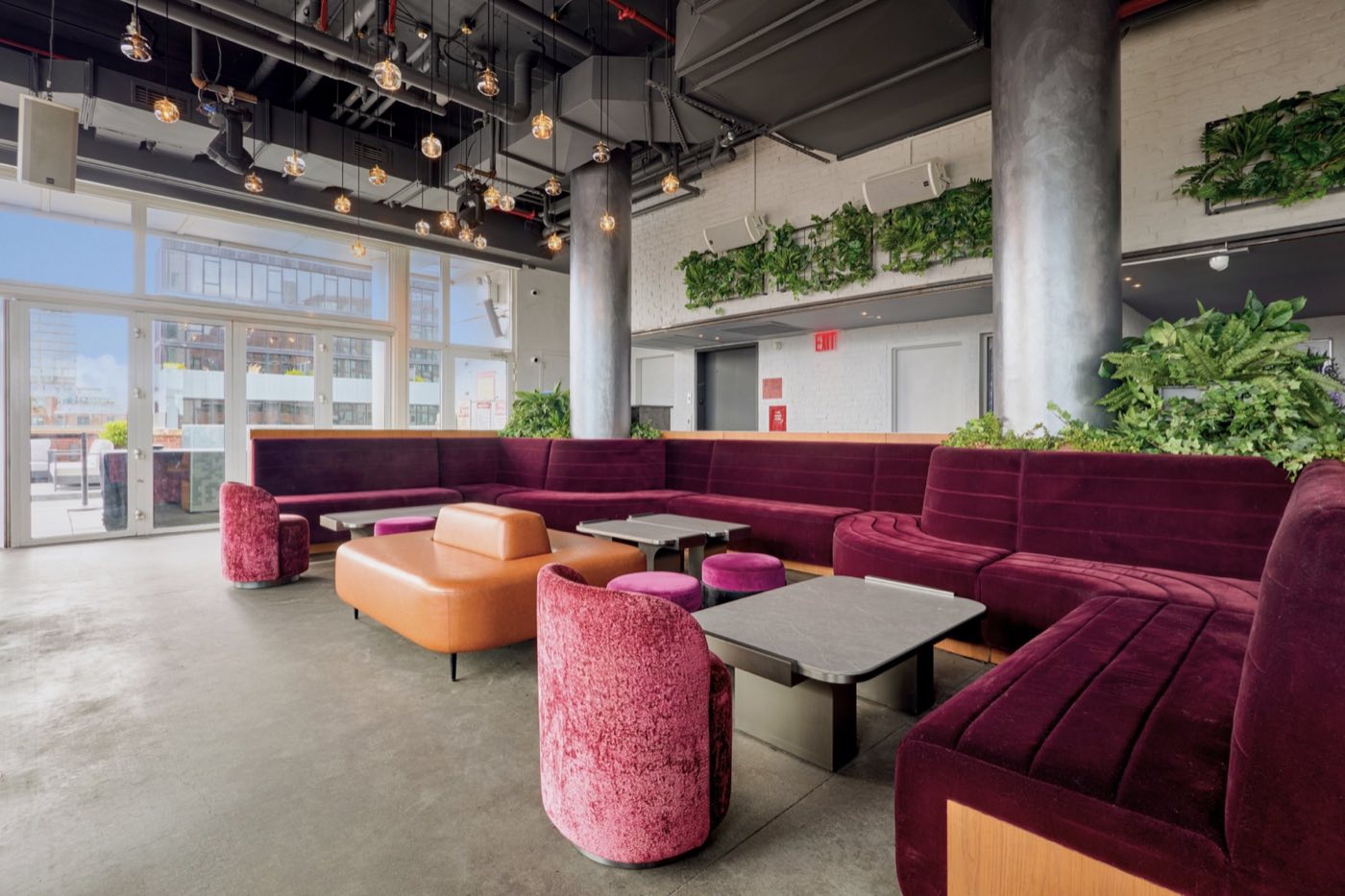 Plum velvet banquettes, leather ottomans and planters inside the rooftop bar
