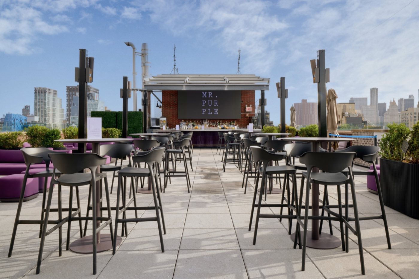 Pool terrace with high tables, bar stools and an outdoor bar under blue sky