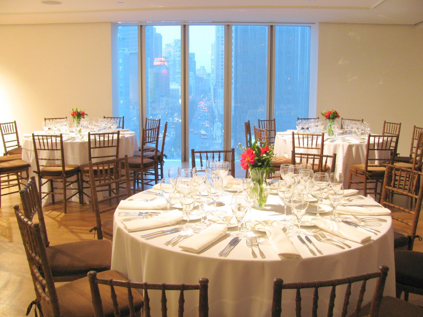 Seventh floor set with round dinner tables before tall windows over Central Park South