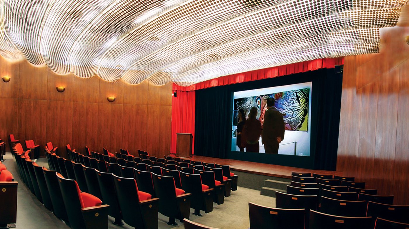Theater with rows of seats, walnut walls and a curved gold ceiling