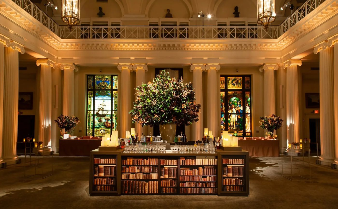 Columned library with a gallery rail, stained glass and a book-lined bar