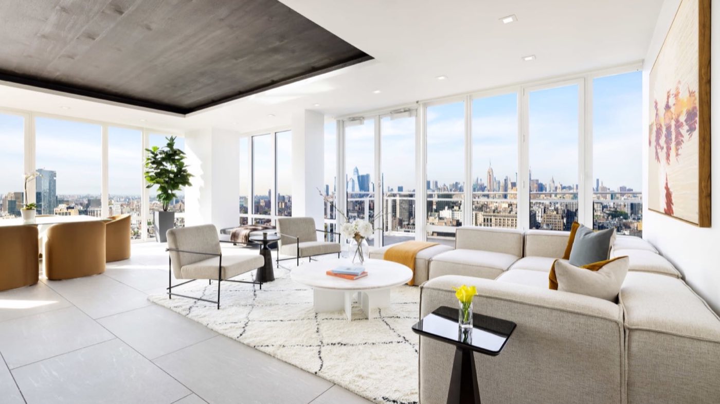 Penthouse living room with lounge seating and floor-to-ceiling windows over the skyline