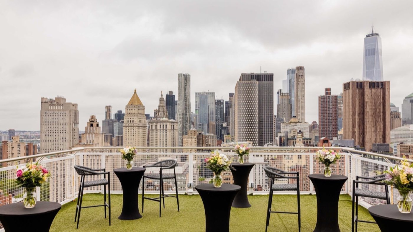Penthouse terrace set with cocktail tables and a view toward downtown Manhattan