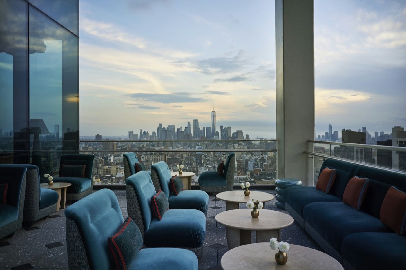 Open-air terrace with blue lounge chairs and a view south over lower Manhattan