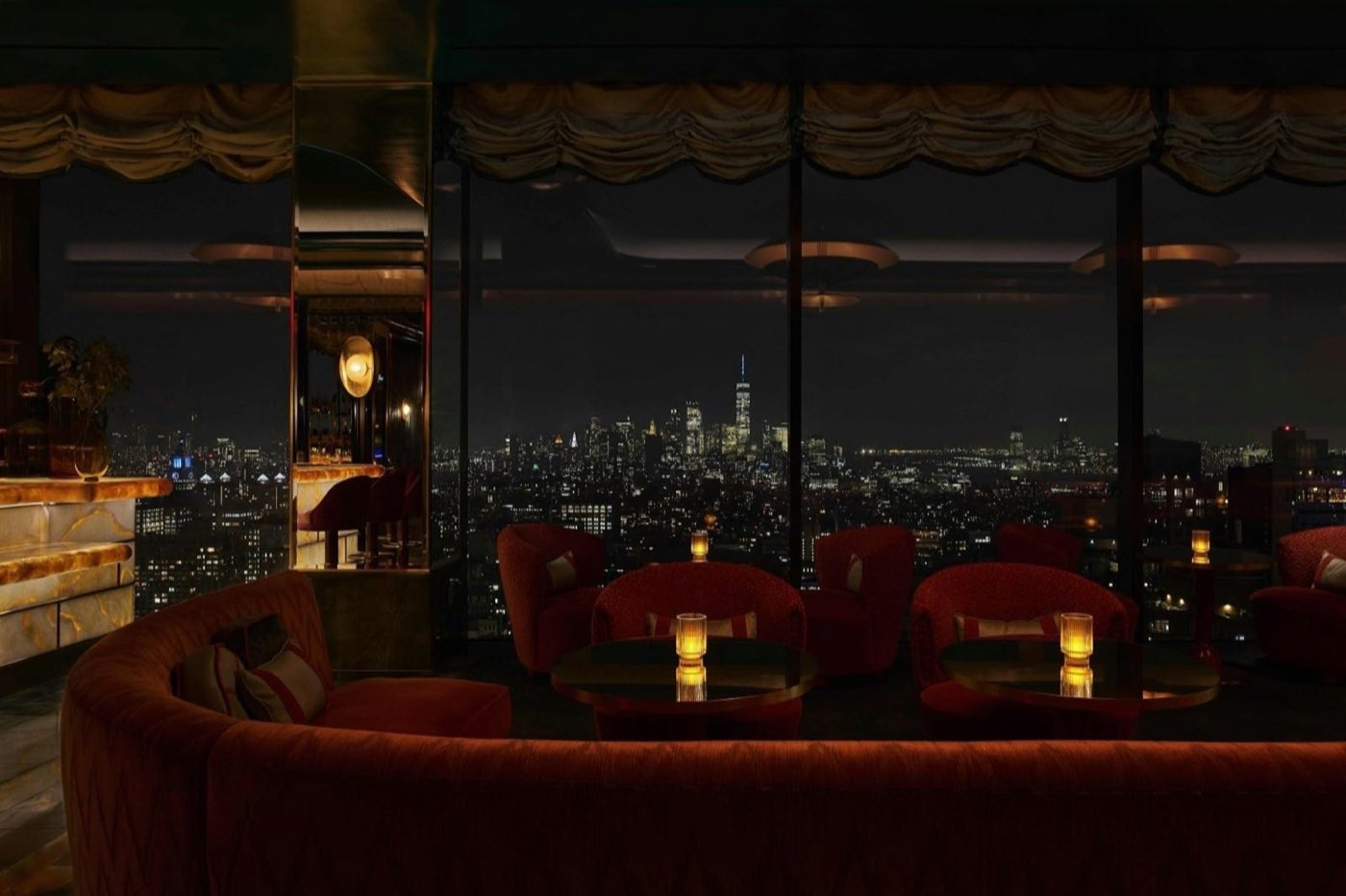 Lounge at night with candlelit tables and a wall of windows onto the skyline