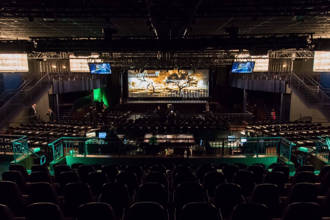Main floor set with rows of seats facing the stage and screens