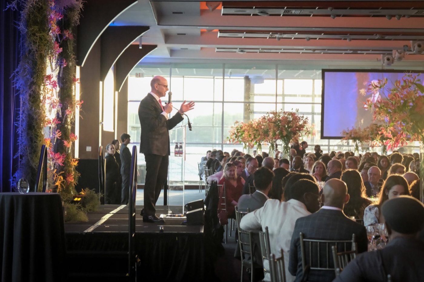 Speaker at a podium addressing a seated dinner in the riverfront ballroom