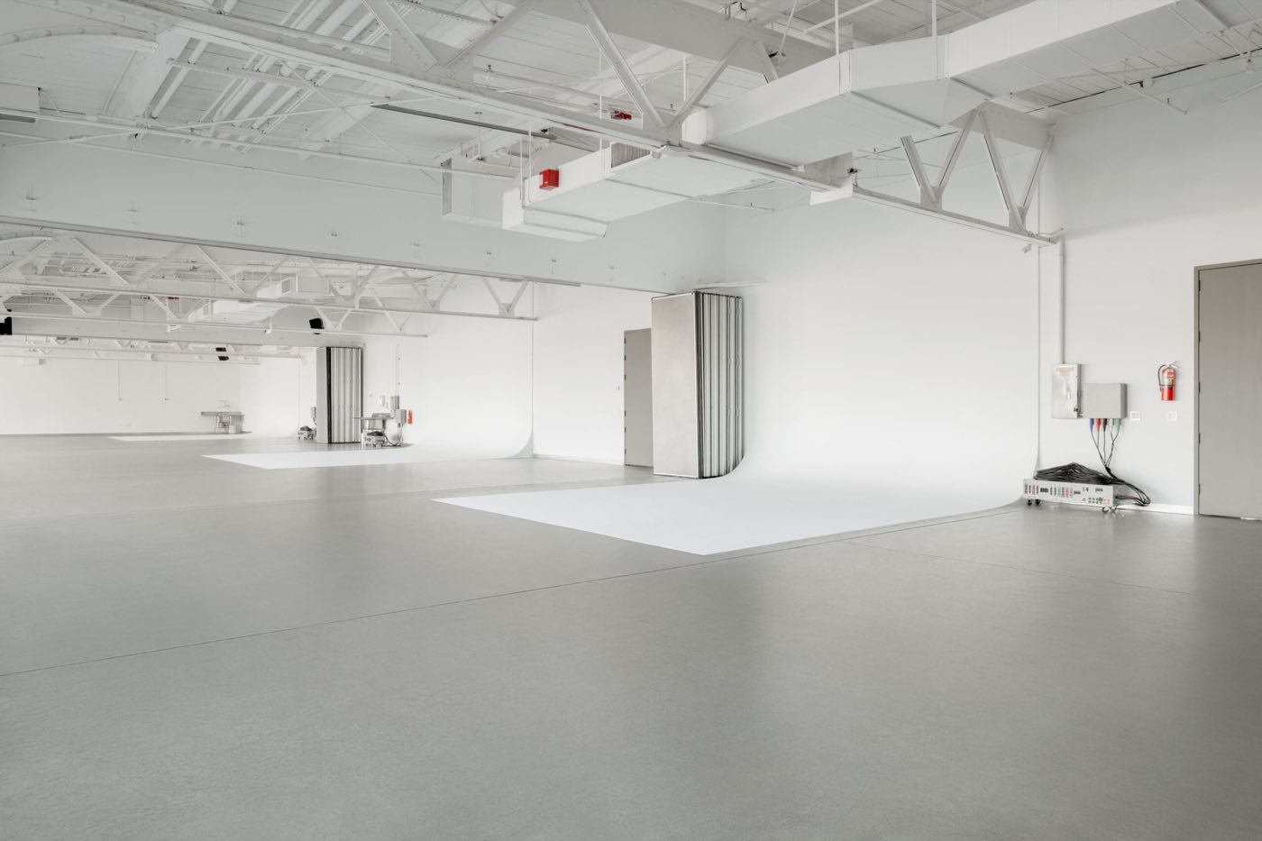 Empty joined daylight studios with white walls, cycloramas and concrete floors