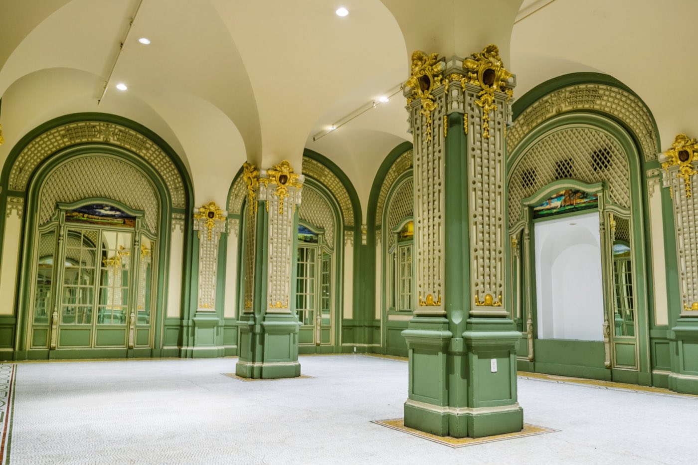 Vaulted room with green and gold columns, arched doors and a tiled floor