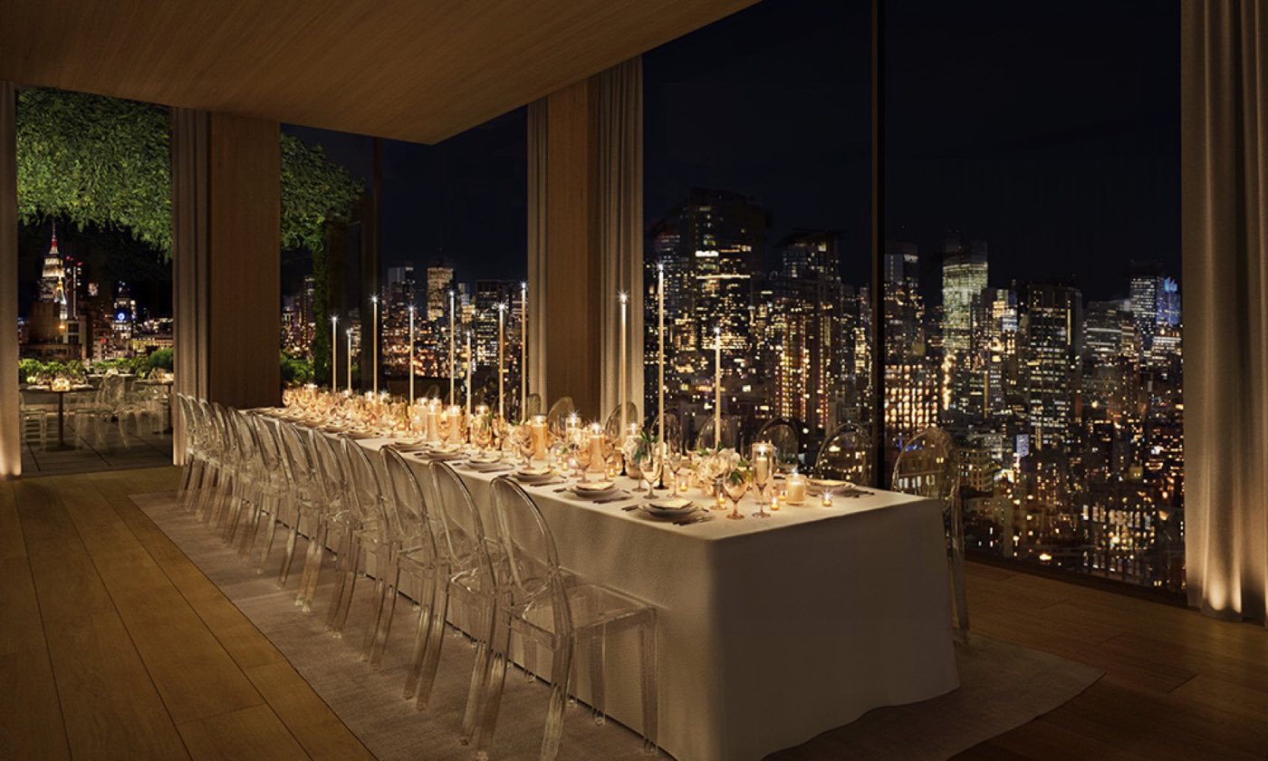 Long dinner table in a high-floor room with floor-to-ceiling windows over the night skyline