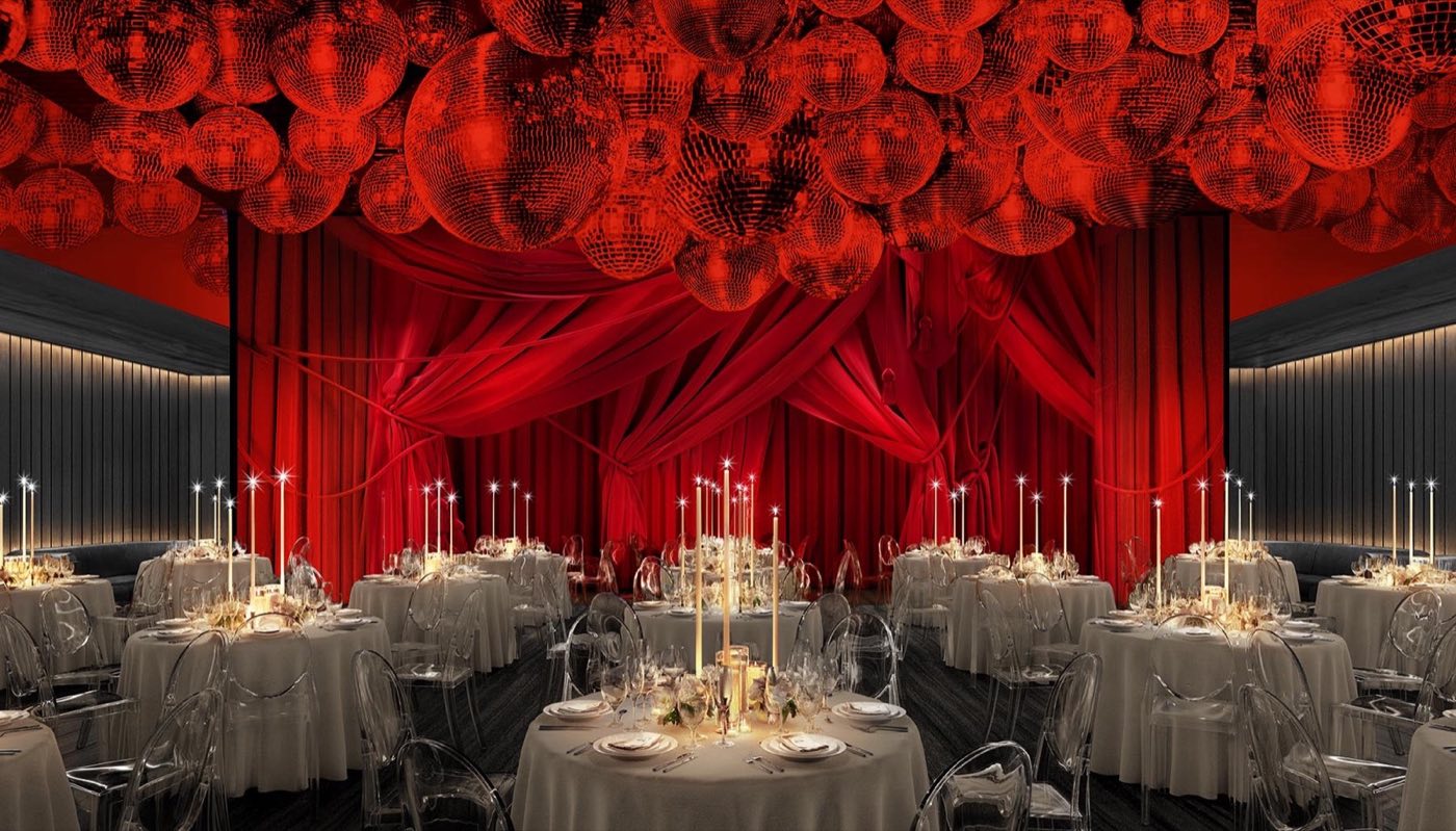 Dining room set with round tables beneath red curtains and a ceiling of mirror balls