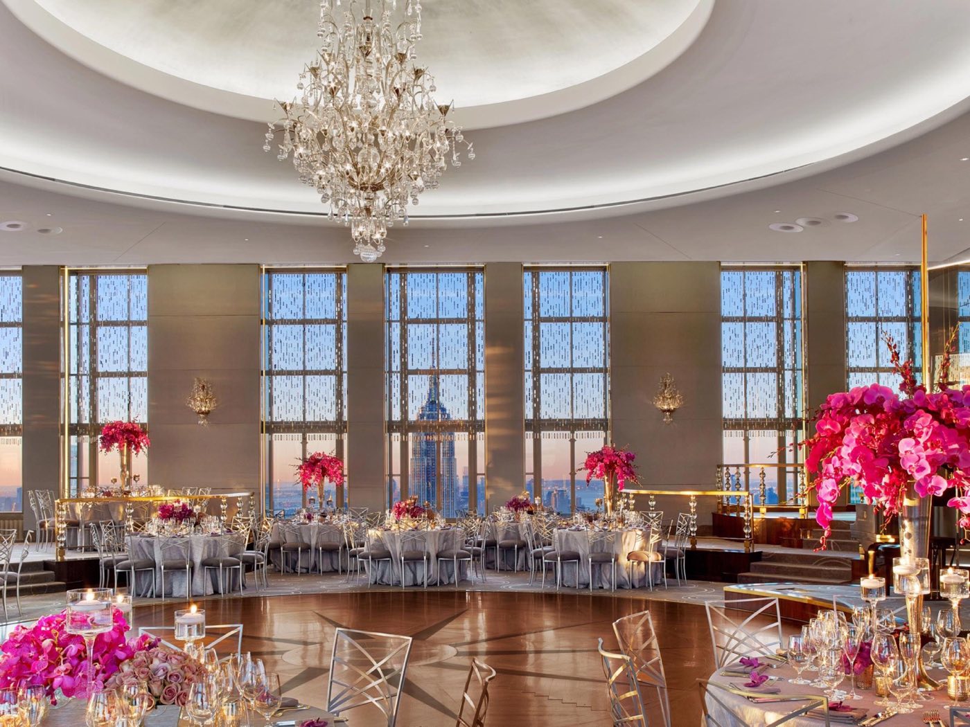 Dinner tables around the dance floor with the Empire State Building visible through tall windows