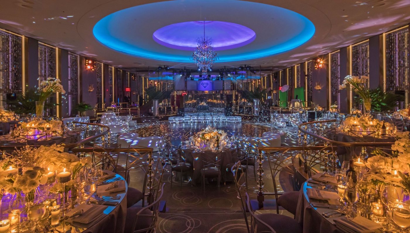 Candlelit dinner tables filling the room beneath the blue-lit dome and chandelier