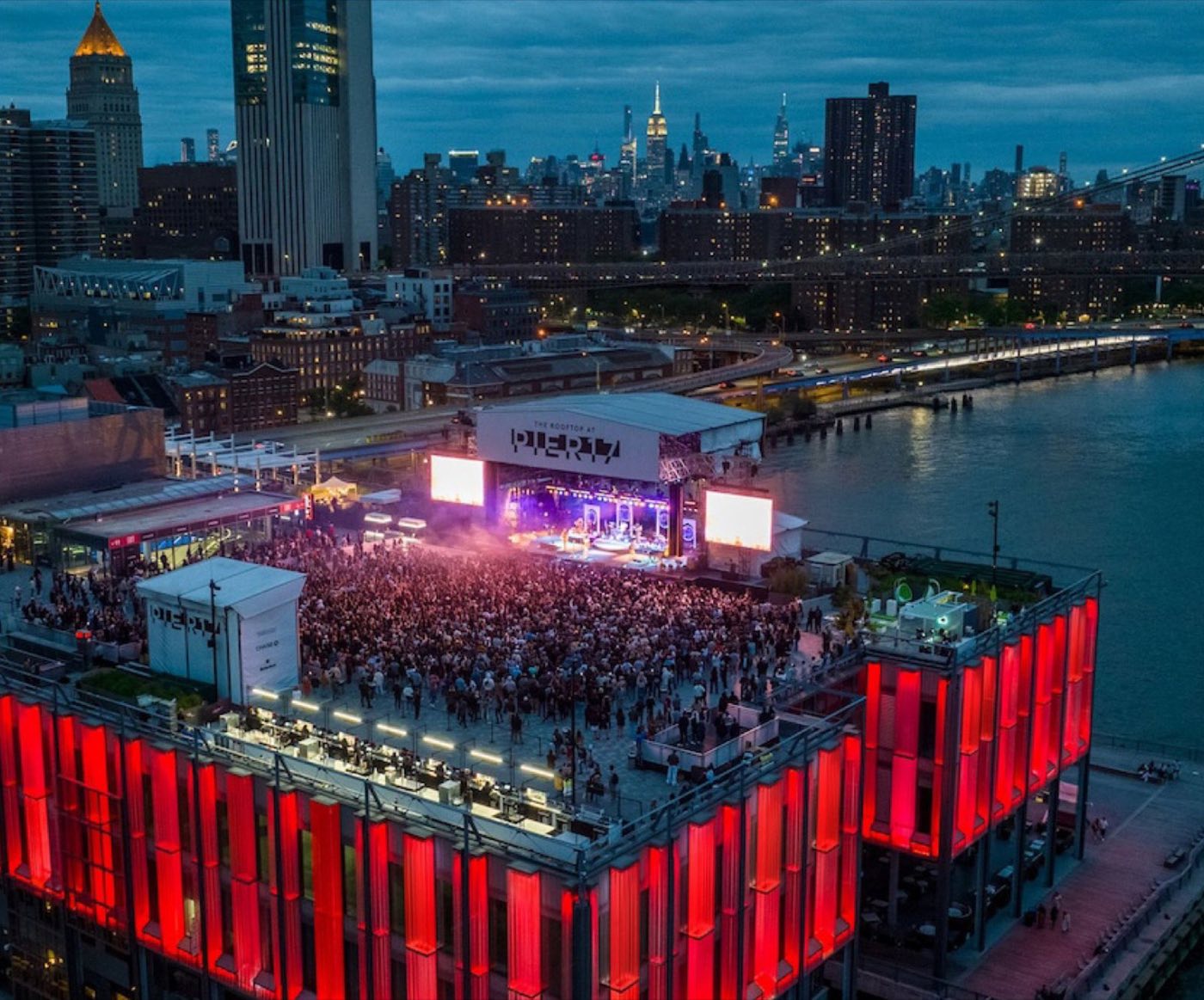 Aerial view of the rooftop during a concert with the stage and river beyond