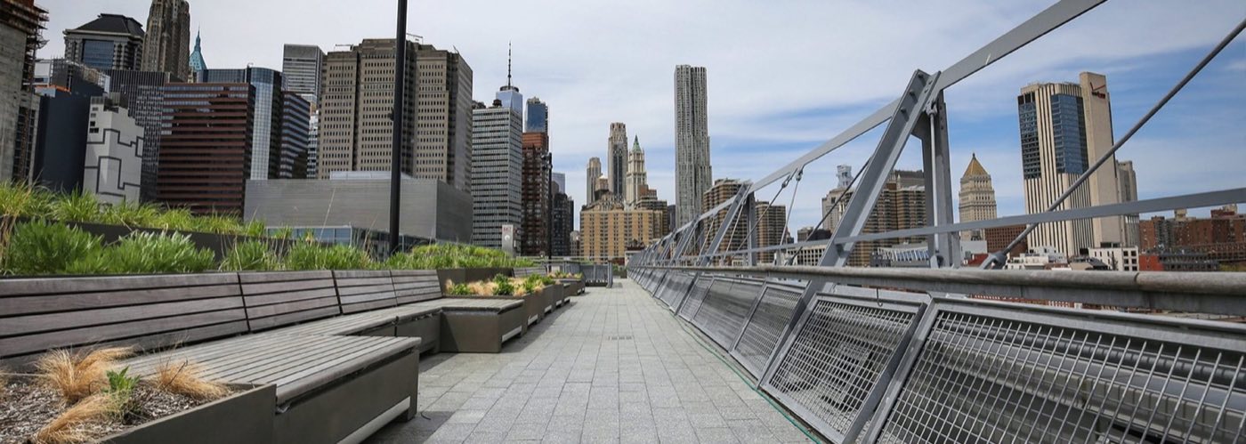 Open rooftop promenade with planters, railings and the downtown skyline