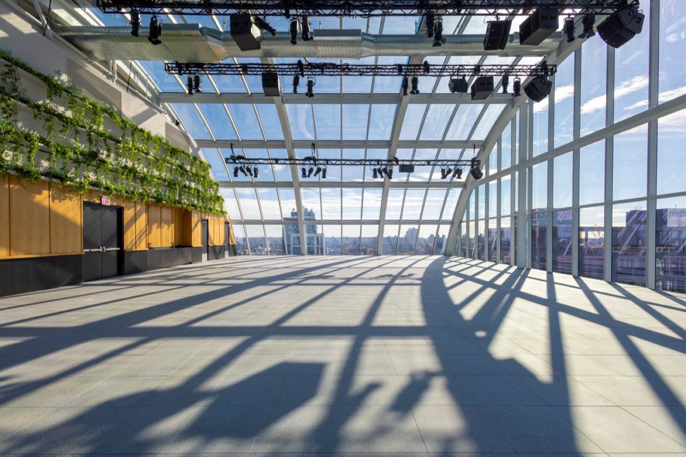 Empty glass-domed penthouse floor with lighting truss, green wall and city view