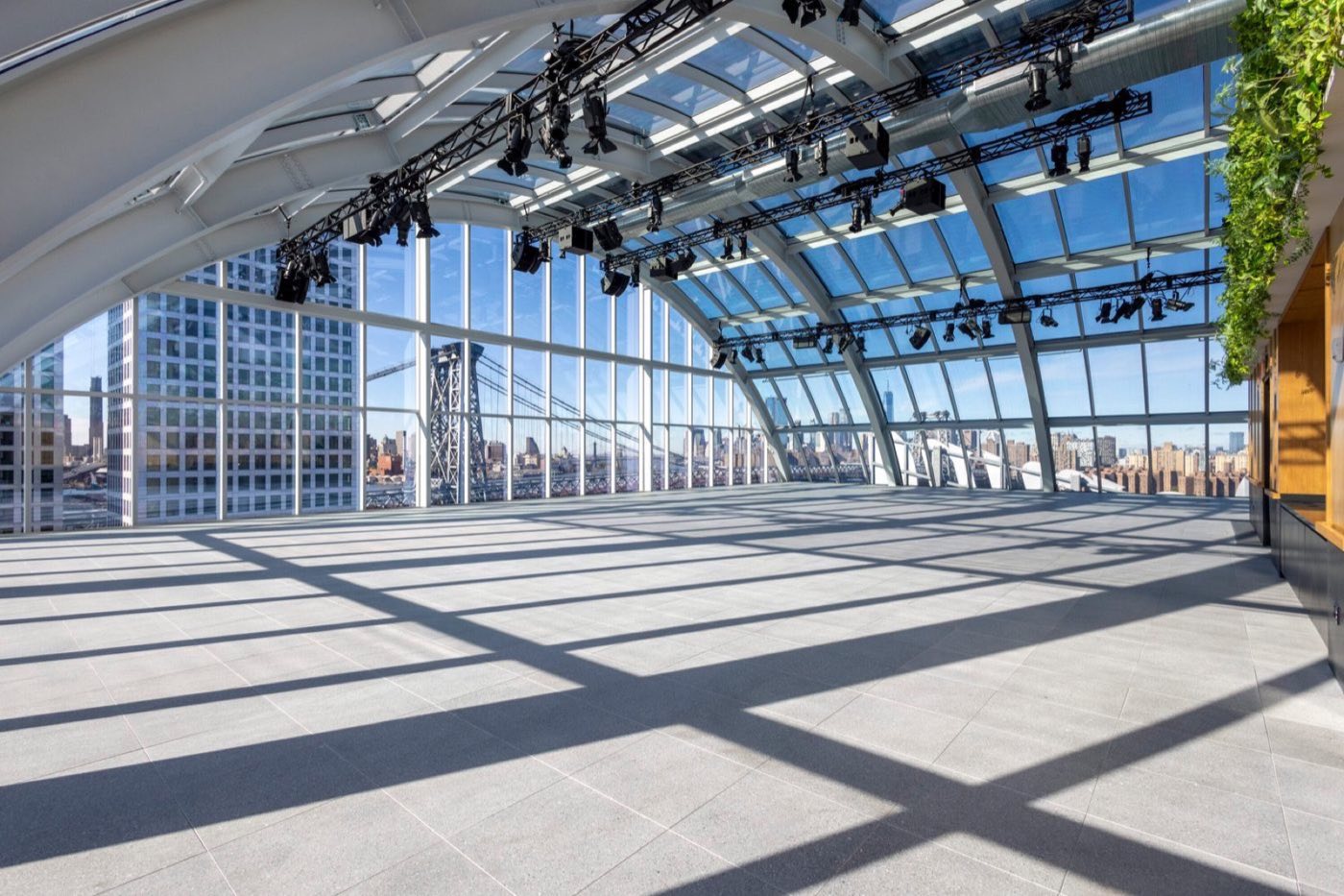 Glass-domed event space with rigging, sunlight shadows and Williamsburg Bridge view