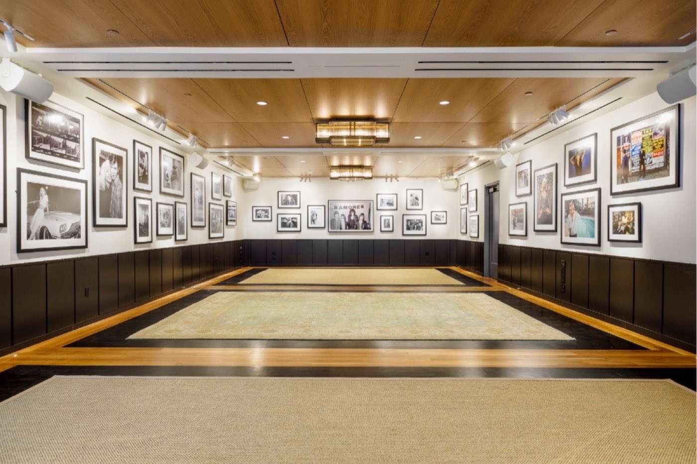 The Gallery event room, empty, with framed photographs on the walls and a large rug