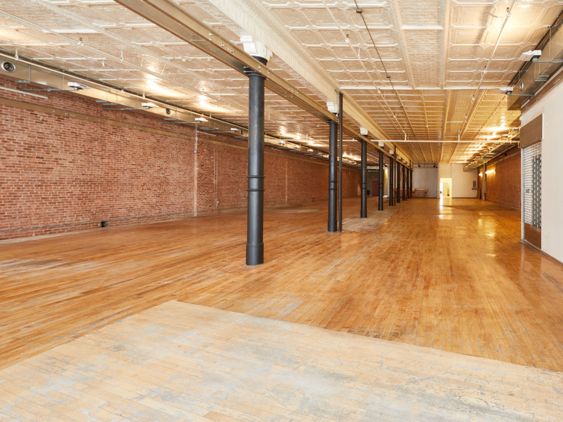 Empty loft running deep into the building with brick walls and warm wood floors