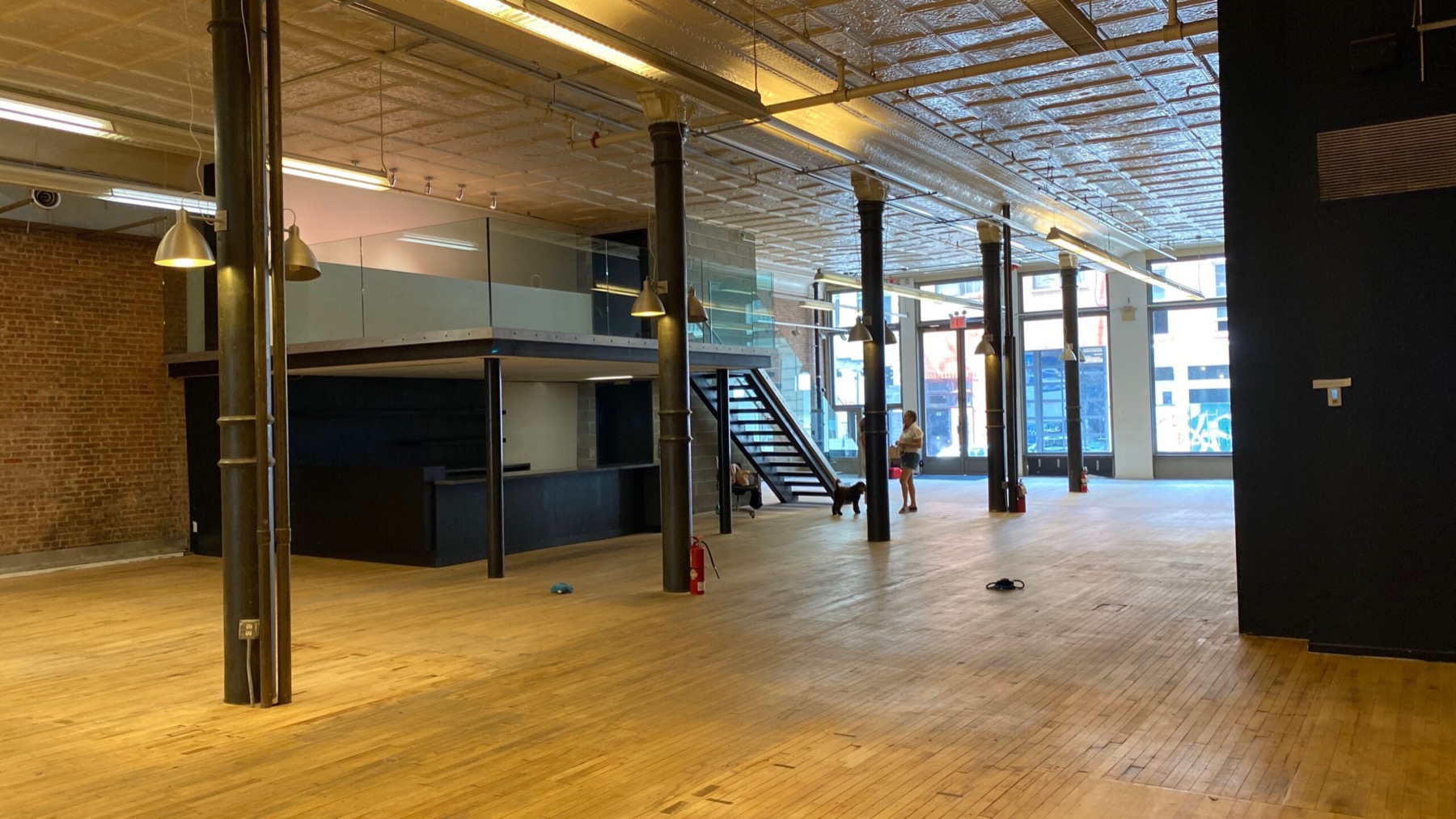 Empty street-level loft with iron columns, tin ceiling, hardwood floor and a mezzanine bar